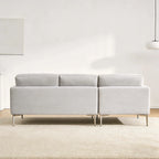 Gray sectional sofa in a minimalistic room with white walls and a light rug.