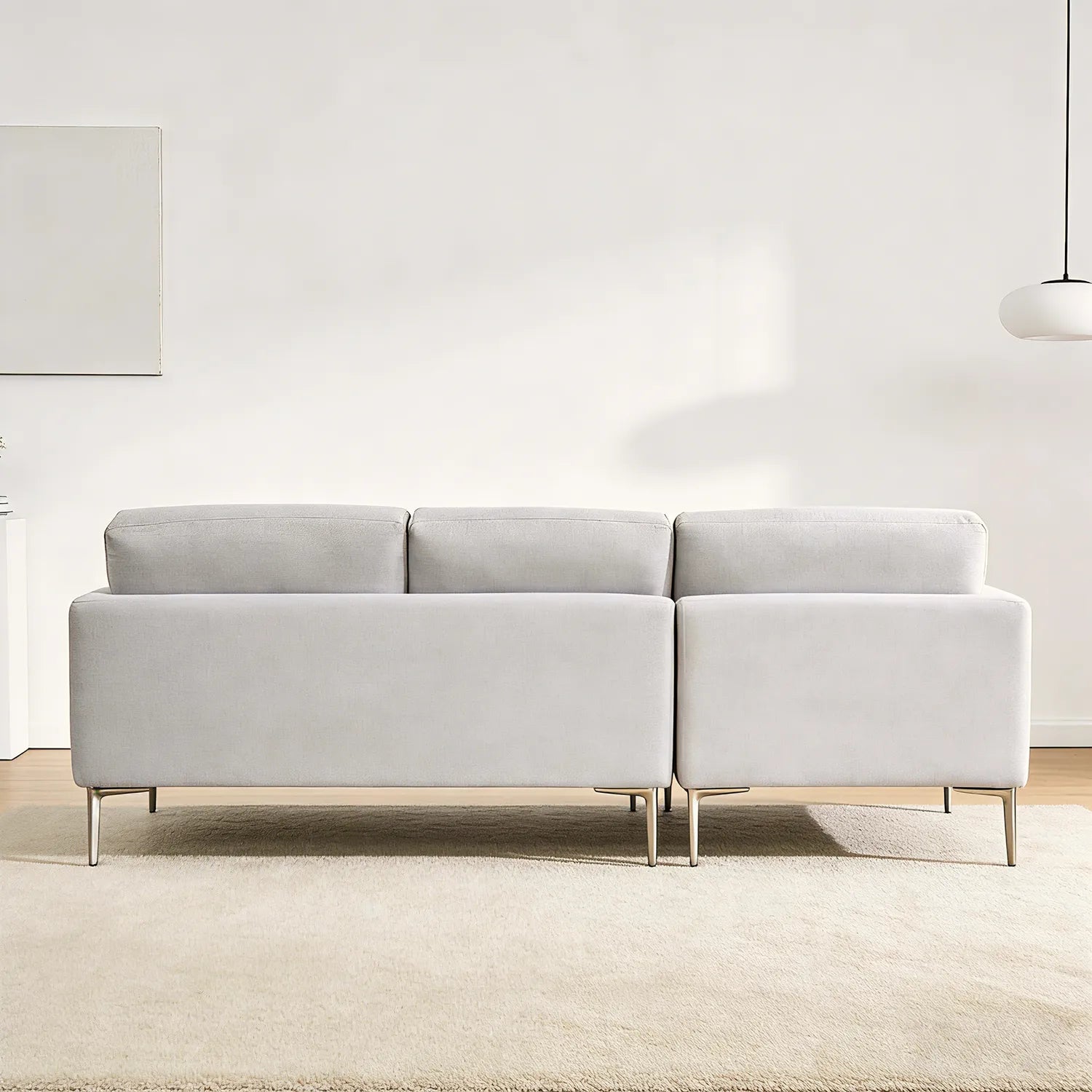 Gray sectional sofa in a minimalistic room with white walls and a light rug.