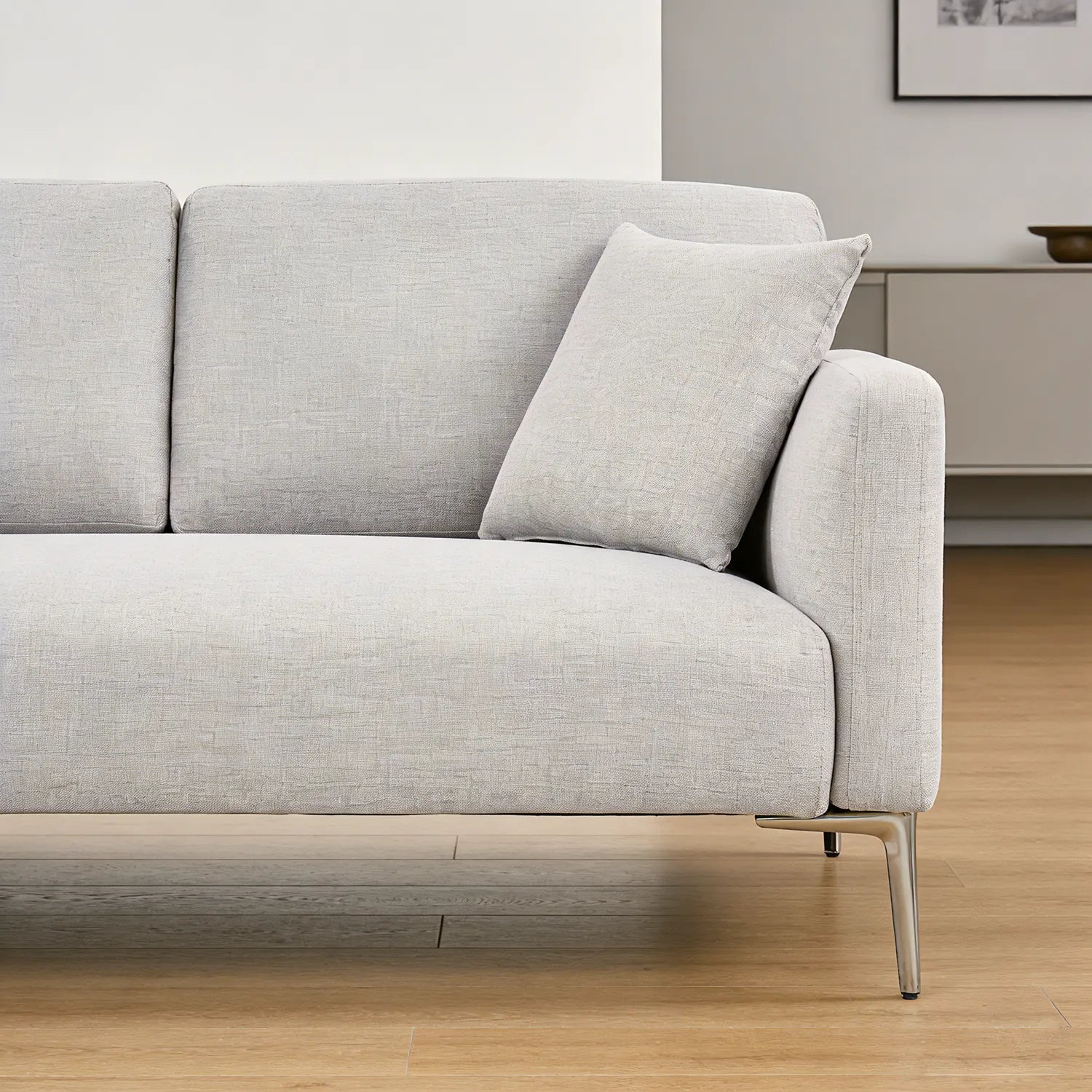 Gray sofa with a pillow on a wooden floor in a room.