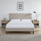 Beige upholstered bed with matching nightstands and a lamp in a bedroom setting.