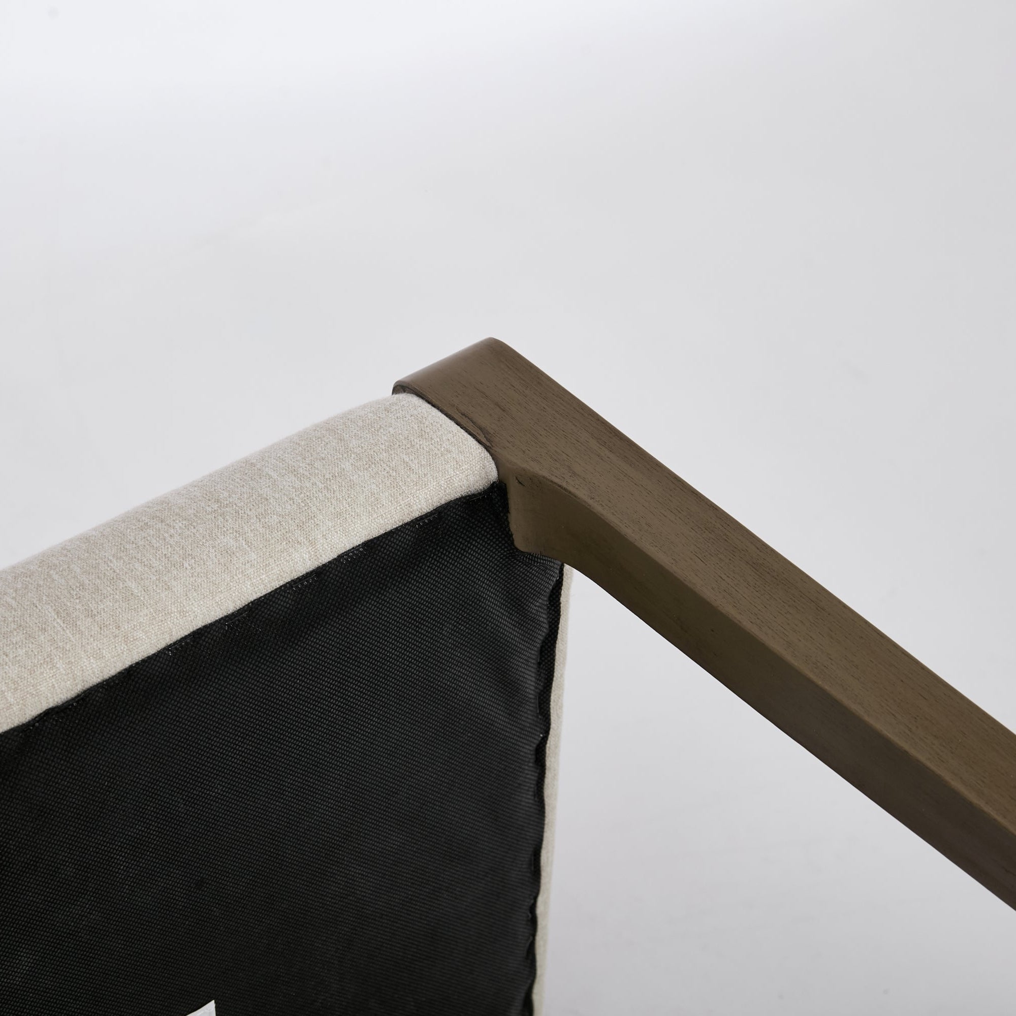 Corner of a piece of furniture with wooden armrest and fabric seat on a white background